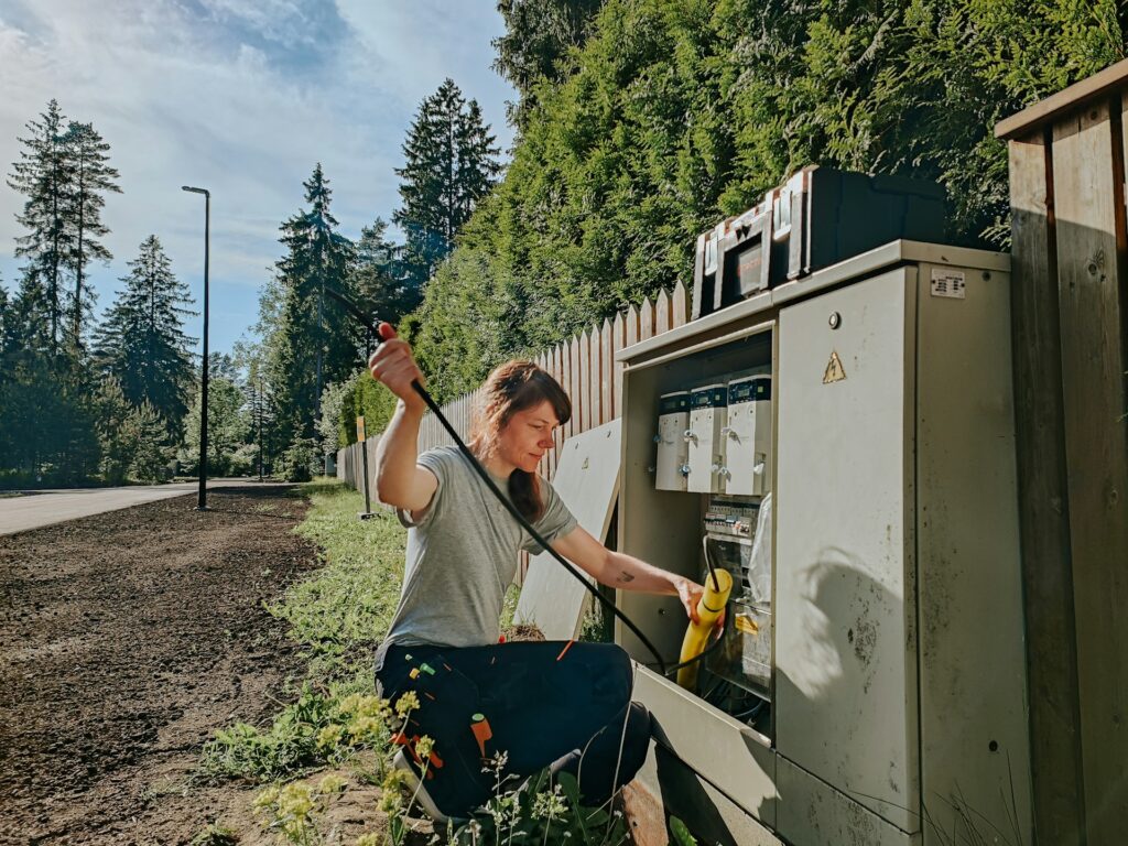 Female electrician working on an outdoor electrical panel, representing diversity and technical skills in electrical contracting